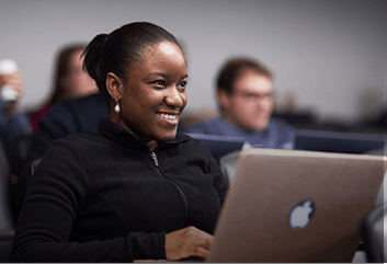 Smiling Student in class with an Apple laptop